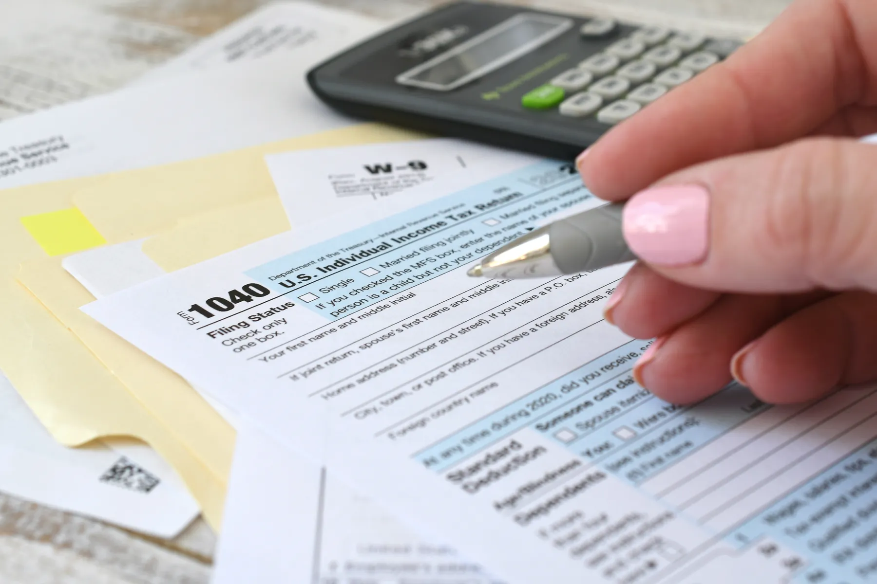 A 1040 tax return, W-9 and calculator on a desk